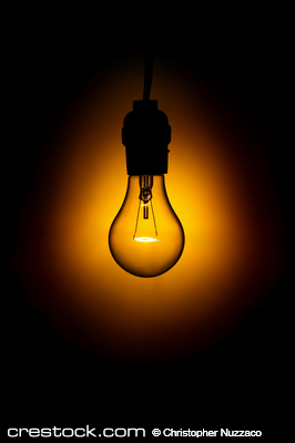 Glowing light bulb against black background.